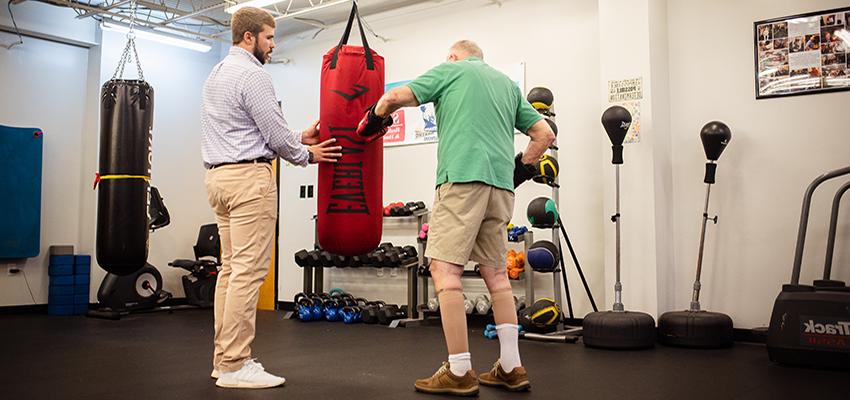 Dylan Thomas, right, an exercise science major, works with patients battling Parkinson’s disease at Saad Healthcare’s Rock Steady Boxing program in Mobile. 